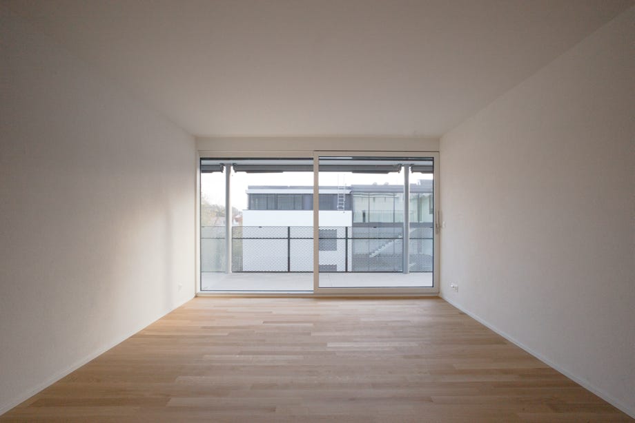 Innenansicht Zimmer mit Verglasung und Balkon. Hansjörg Betschart Architektur ©.