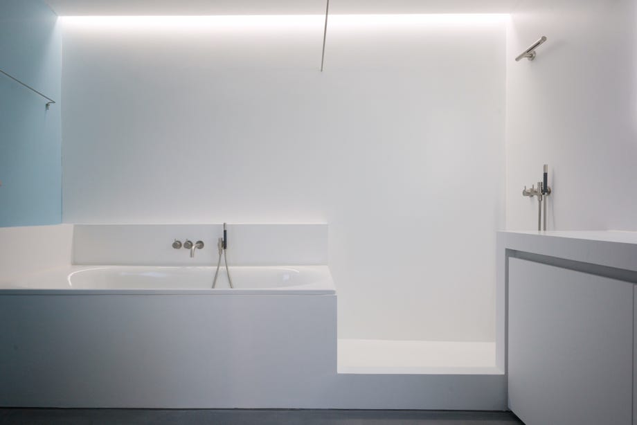 Innenansicht Badezimmer mit Badewanne, Dusche und indirektem Licht. Hansjörg Betschart Architektur. 