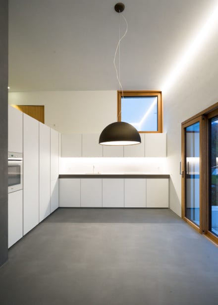 Innenansicht Küche mit überhoher Raumhöhe und Lichtfuge. Hansjörg Betschart Architektur. 