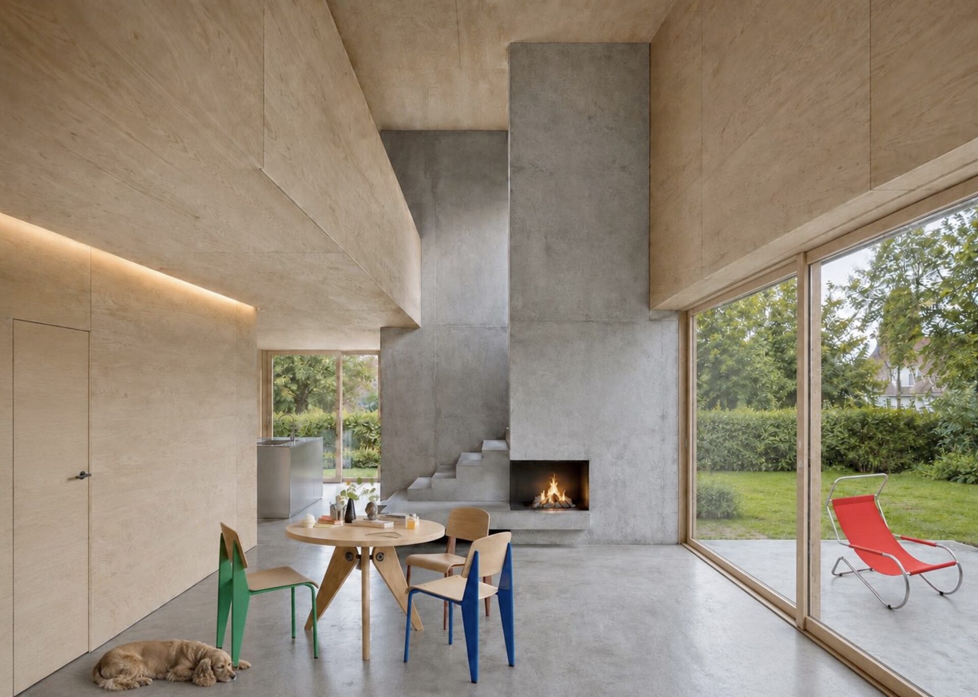 Wohnzimmer im Holzbau mit Betonboden, indirekter Beleuchtung und Cheminée.